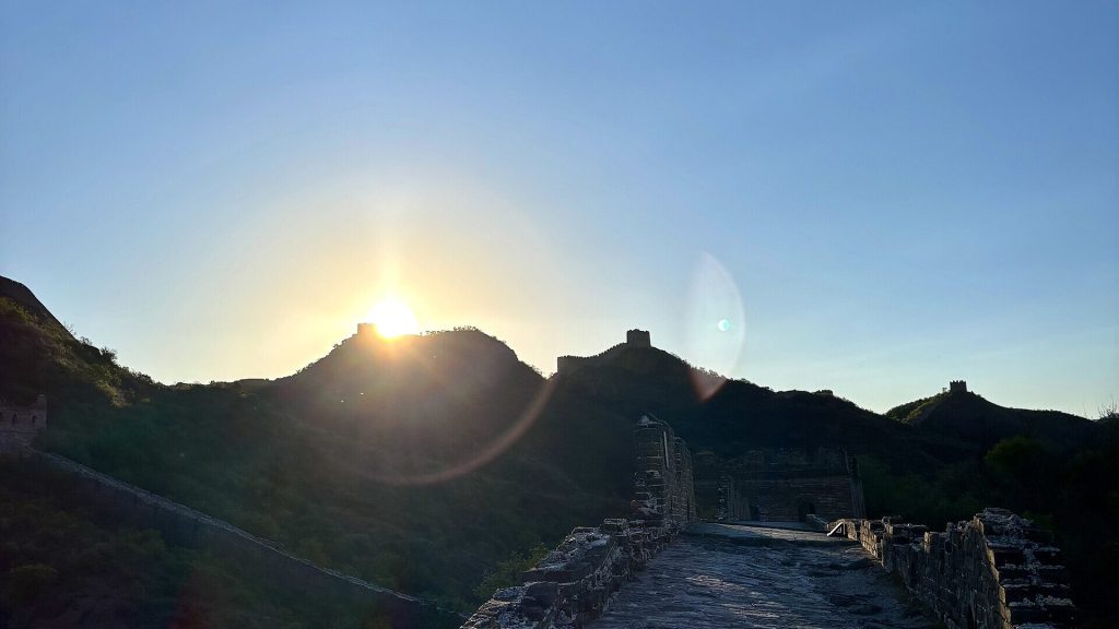 Great Wall of China silhouette at sunrise over rolling mountain ridges